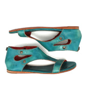 Bed Stu's Soto sandals in teal leather feature open toes, cushioned footbeds, side cutouts, decorative stitching, and snap button accents—stylish and comfortable for everyday exploring. Shown here side by side on a white background.