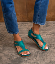 Wearing Bed Stu Soto teal leather sandals with a cushioned footbed and cutout design, paired with cropped blue jeans—ideal for everyday exploring on concrete floors.