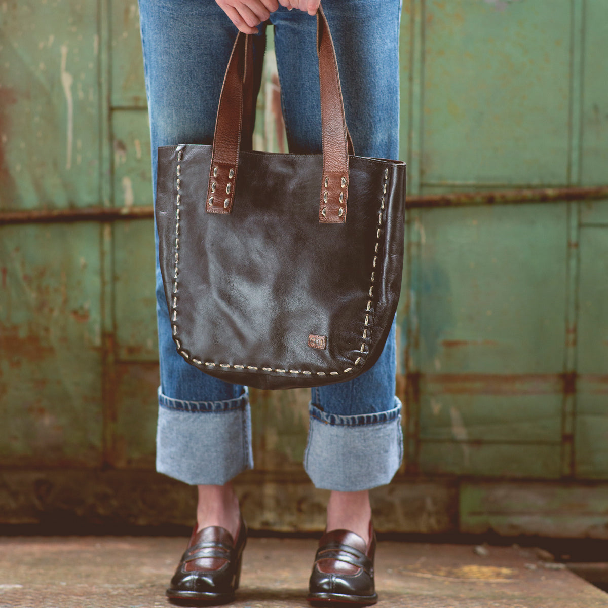 A woman holding a vintage-chic Bed Stu Stevie leather tote bag.