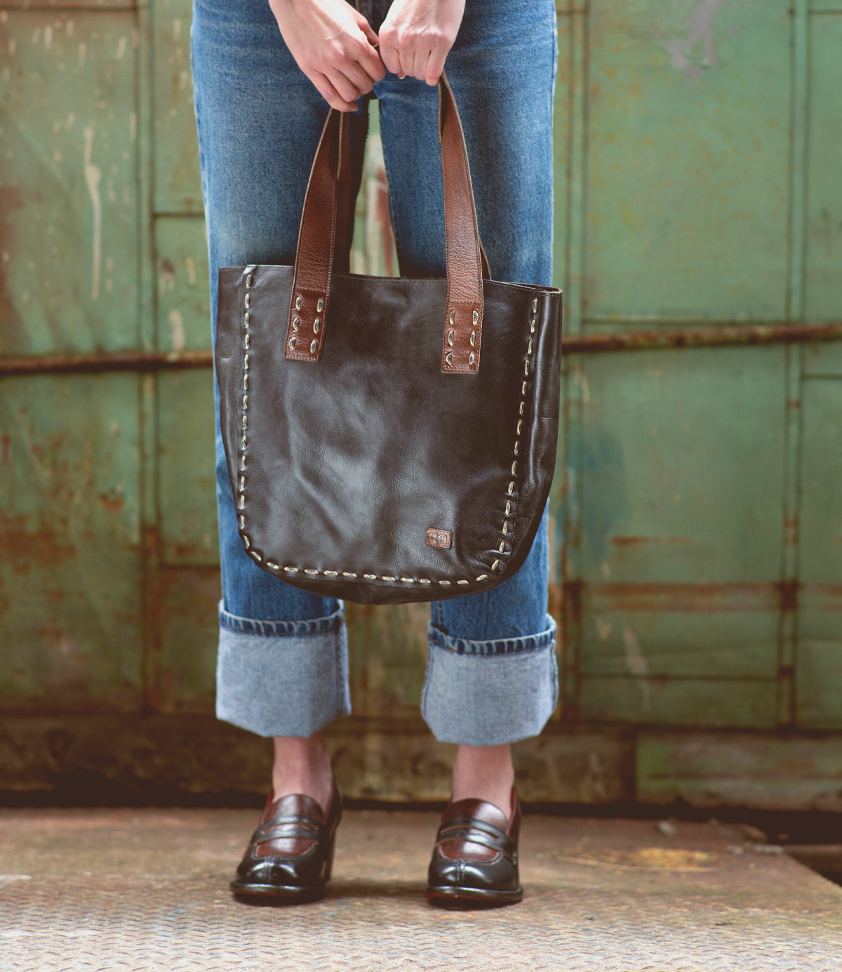 A woman holding a vintage-chic Bed Stu Stevie leather tote bag.