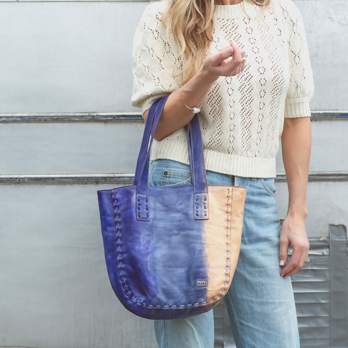 A woman holding a Bed Stu Stevie tote bag in blue and tan.
