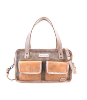 The Bed|Stü Stuffy is a rectangular leather handbag with a structured silhouette, featuring two front pockets, double handles, and a removable shoulder strap. Displayed against a white background, this preppy bag offers a spacious interior to hold all your essentials.
