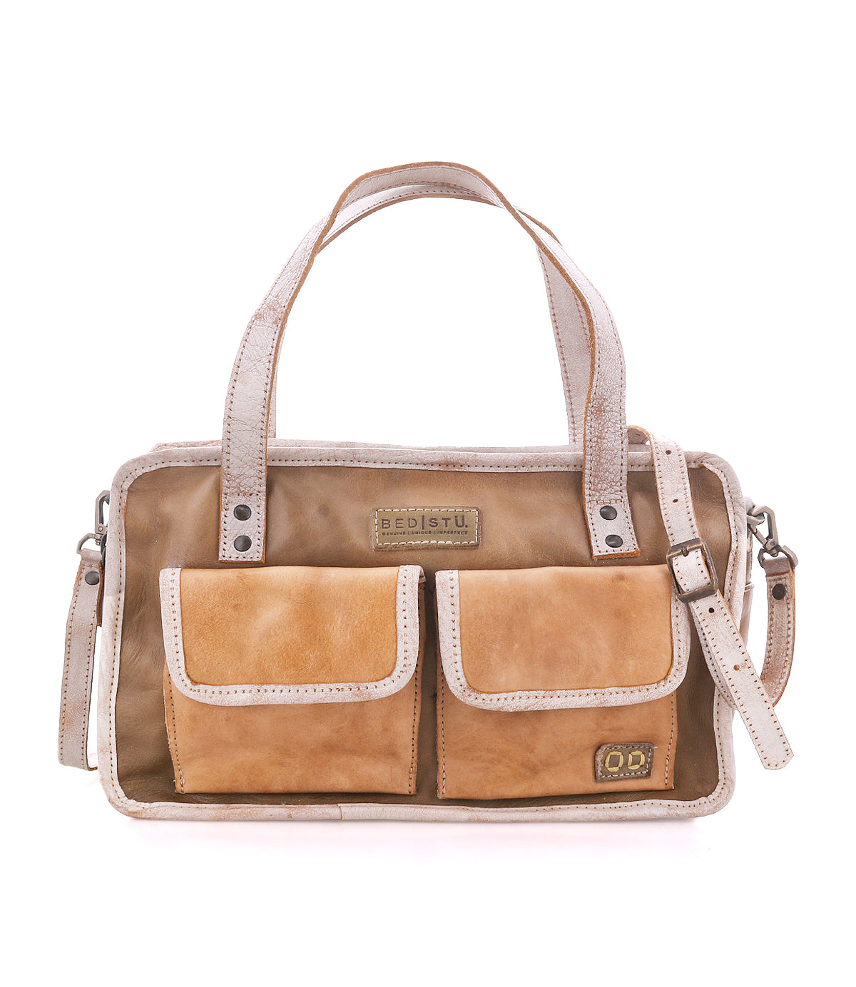The “Stuffy” handbag by Bed|Stü is crafted in tan leather with a structured silhouette, featuring two front pockets, dual top handles, a removable shoulder strap, decorative stitching, and branded labels displayed on the front for a preppy look.