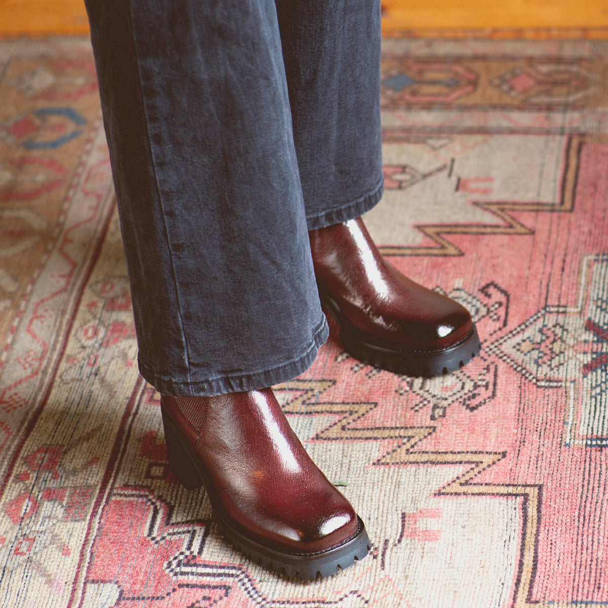 A person standing on a rug wearing Bed Stu Italian leather Chelsea boots.
