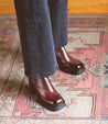 A person standing on a rug wearing Bed Stu Italian leather Chelsea boots.