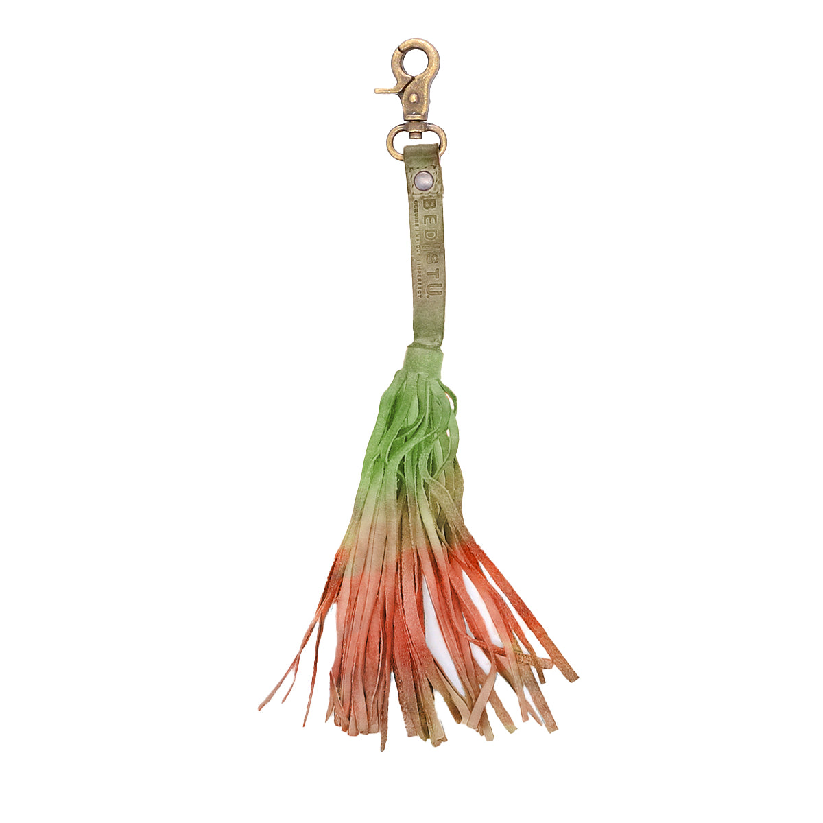 The Bed Stu Tassel Clip features a multicolored ombre tassel with a metal clasp and high-quality leather strap, showcasing personal expression as the colors shift from green to orange and beige.