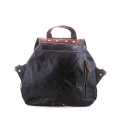 The Bed Stu Teji is a black leather statement backpack with brown accents, featuring a front zipper pocket, top handle, and adjustable side straps, shown against a white background.