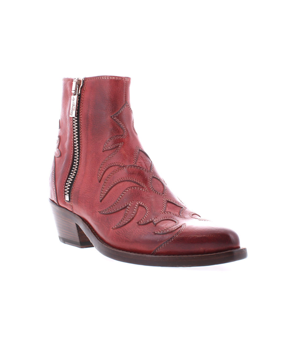 The Bed Stu Tentativa is a red leather ankle boot featuring artisan details, decorative stitching, a side zipper, low block heel, and a slightly pointed toe.