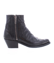The Bed Stu Tentativa is a black leather ankle boot featuring artisan details, a side zipper, decorative stitching on the upper, and a low block heel, shown in profile against a white background.