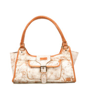 The Bed Stu Unbending is a rectangular cream and tan washed leather shoulder bag featuring dual handles, a buckle-front flap pocket, and a distressed finish.