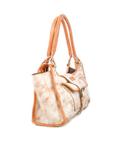 The Bed Stu Unbending is a tan and beige washed leather shoulder bag featuring double handles, side pockets, and a buckle-front flap closure, shown against a white background.