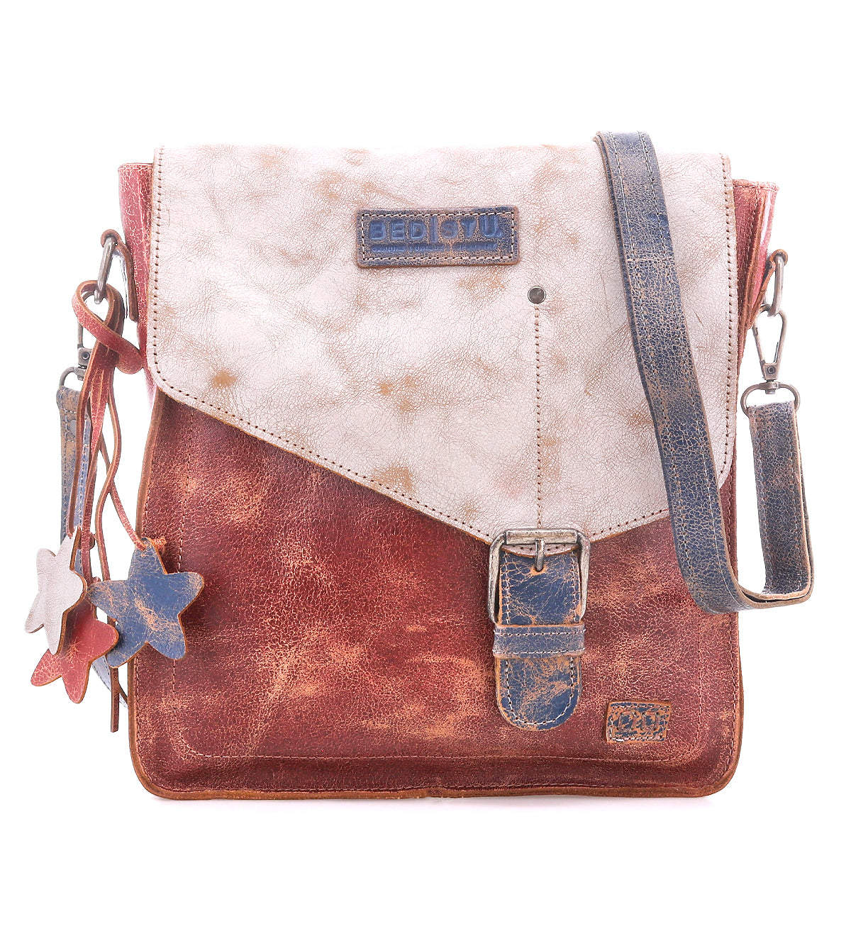 The Venice Beach by Bed Stu is a square crossbody bag made from full-grain leather in a distressed brown and white finish, featuring a front buckle, star-shaped charms, and an adjustable strap for versatile styling.