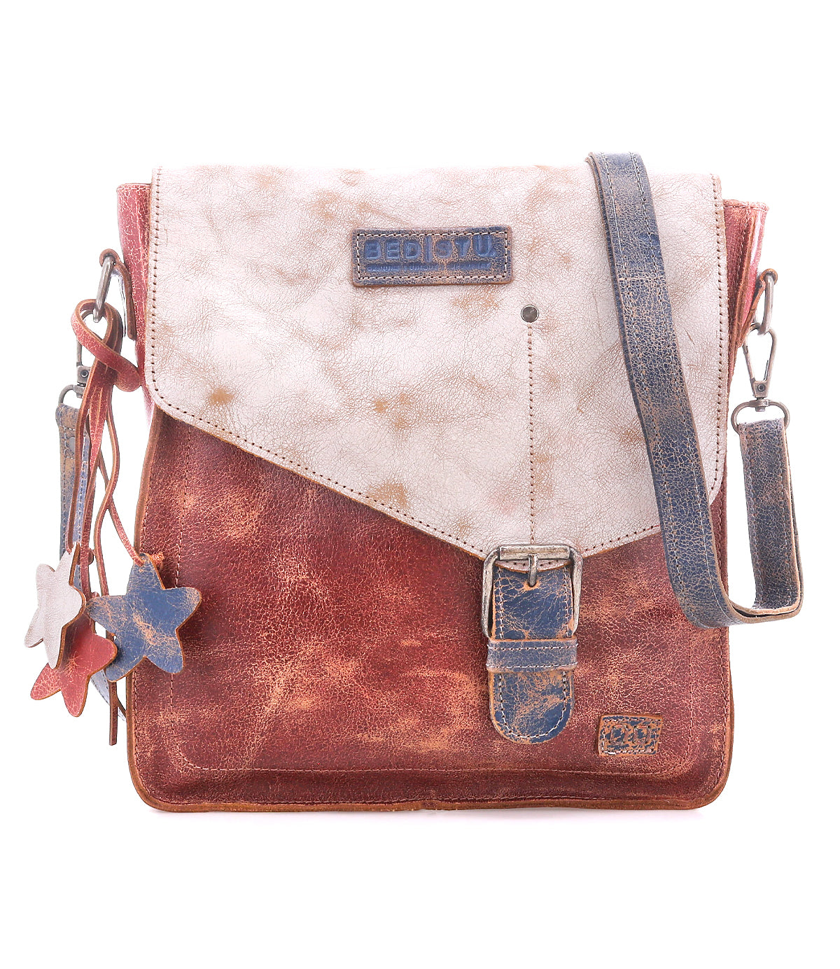 The Venice Beach by Bed Stu is a square crossbody bag made from full-grain leather in a distressed brown and white finish, featuring a front buckle, star-shaped charms, and an adjustable strap for versatile styling.