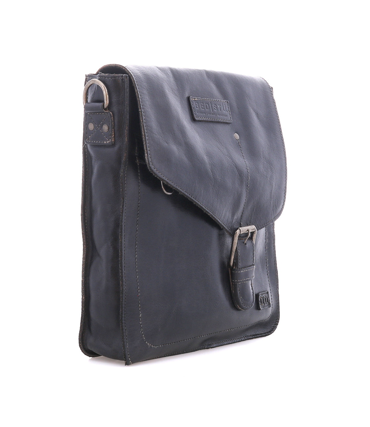 The Bed Stu Venice Beach is a black full-grain leather shoulder bag with a front flap, buckle closure, adjustable strap, and visible stitching, shown upright on a white background.
