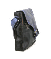 A side view of the Bed Stu Venice Beach handmade leather crossbody bag in black with a blue flap and strap, photographed on a white background.