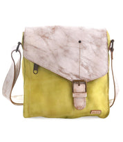 The Venice Beach by Bed Stu is a bohemian-inspired, handmade leather crossbody bag with a yellow body and light brown textured flap. It features a buckle closure and an adjustable shoulder strap, exuding laid-back charm.
