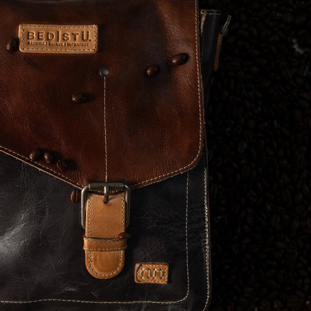 Bed|Stü Venice Beach two-toned brown full-grain leather messenger bag with an adjustable crossbody strap, a buckle closure, and branded leather patches.