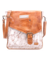 The Bed Stu Venice Beach is a brown and white full-grain leather crossbody bag featuring a front buckle, adjustable shoulder strap, and a visible brand patch on the flap.
