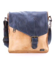 The Venice Beach by Bed Stu is a two-tone, handmade leather crossbody bag, featuring a dark blue flap and beige body. It includes a buckle closure and an adjustable strap. With its bohemian-inspired design, this bag highlights quality craftsmanship, making it both stylish and practical.