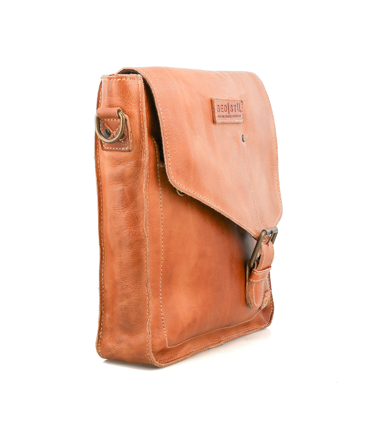 The Venice Beach by Bed Stu is a vintage-inspired tan leather shoulder bag with a flap closure, metal buckle, and side ring for the strap, shown against a white background.