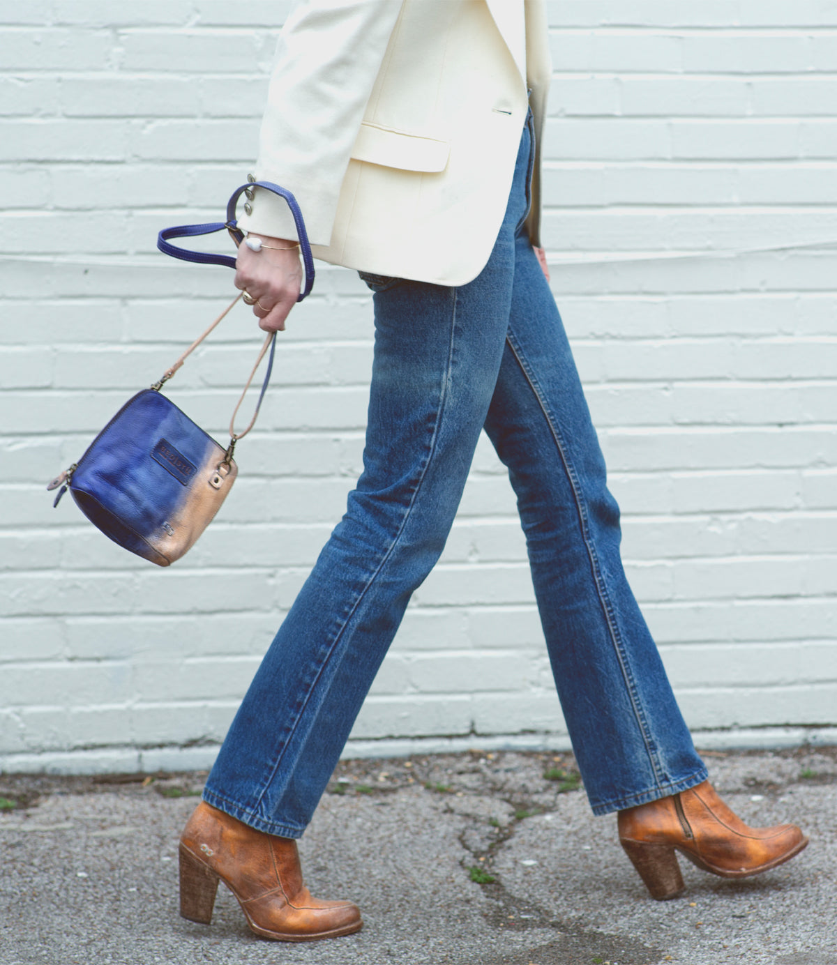 A woman in Ventura jeans and a Bed Stu leather blazer walking down the street.