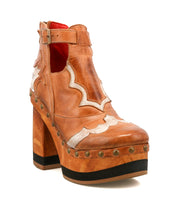 The Bed Stu Viretta is a tan leather platform boot with a chunky handcrafted wooden heel, decorative stitching, silver studs, and a side buckle.