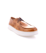 The Webmaster by Bed Stu is a men's sneaker crafted from brown leather, featuring a white sole and dark brown laces. Designed for all-day comfort, it is displayed against a white background.