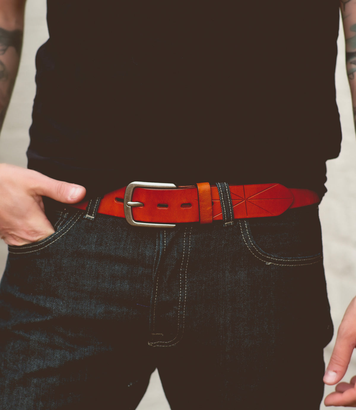 A person wearing a black shirt, dark jeans, and a brown leather Bed Stu Westham belt with a removable silver buckle featuring a stamped star design, shown from the waist down.