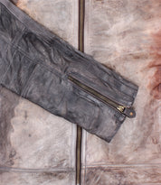 Close-up of the Bed Stu Windfall leather fitted jacket, highlighting a vertical front zipper and a zippered sleeve pocket; features a smooth satinized cotton lining for comfort.