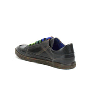 The Bed Stu Wizard is a black, low-profile leather sneaker featuring multicolored laces, blue inner lining, and crossover stitching, displayed from a rear side angle on a white background.