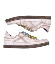 Two distressed off-white Bed|Stü Wizard low-profile sneakers with multicolored laces and crossover stitching, positioned head-to-toe against a white background.