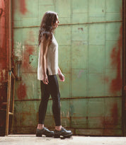 A woman wearing Bed Stu Yazar platform lace-up leather shoes standing in front of a green building.