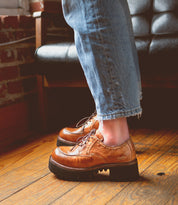 A Bed Stu Yazar wearing a pair of leather shoes on a wooden floor.