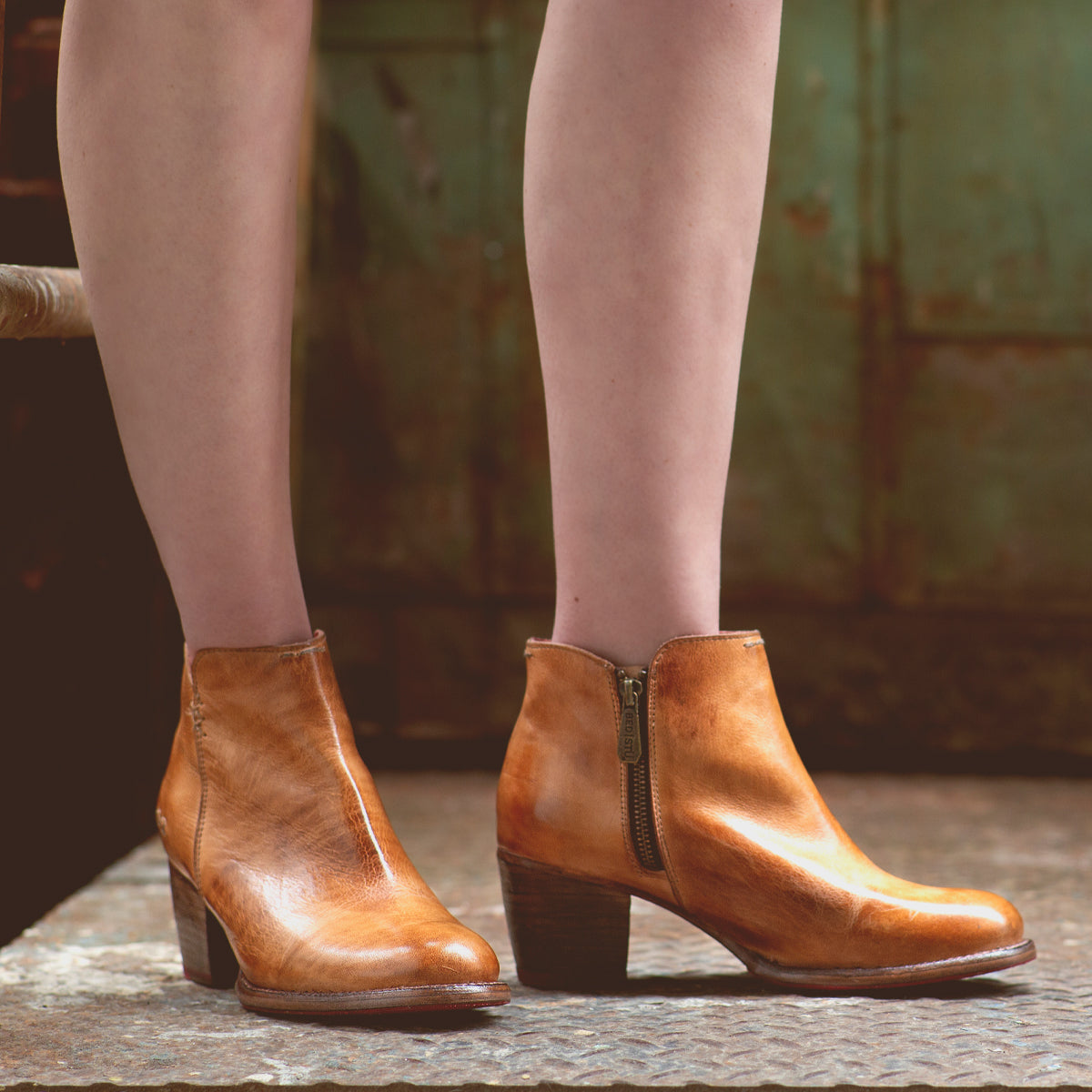 A woman donning a pair of high-heeled, tan leather Bed Stu Yell ankle boots.