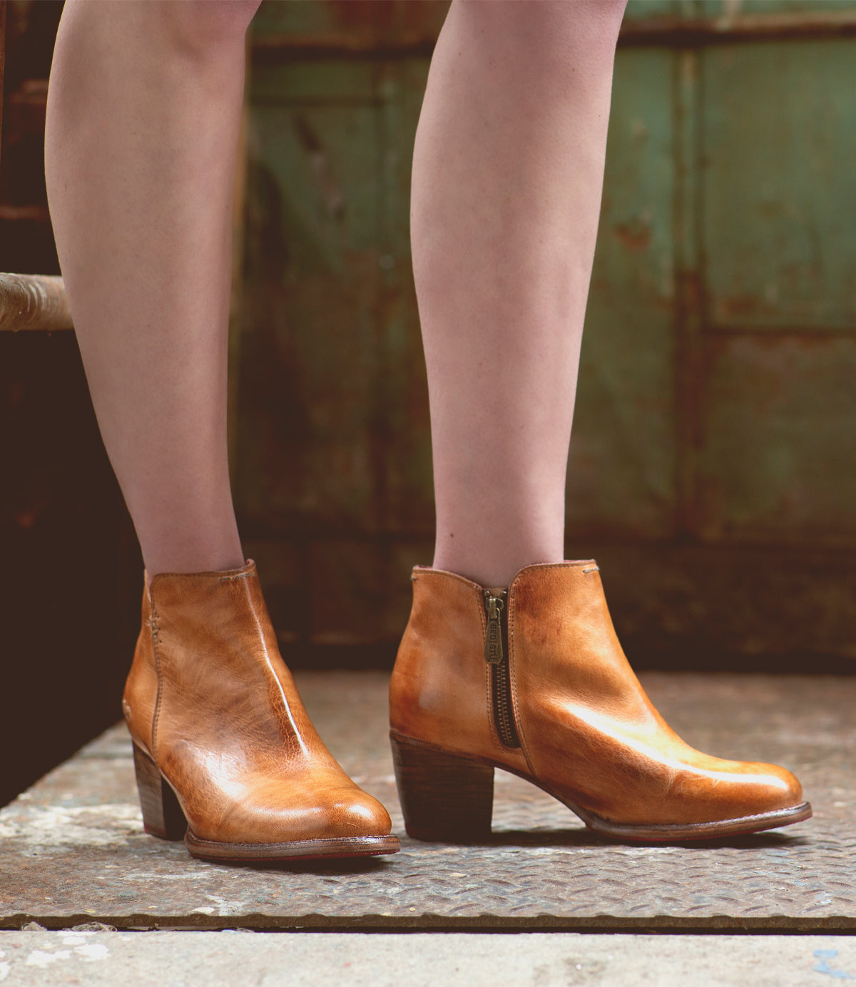 A woman donning a pair of high-heeled, tan leather Bed Stu Yell ankle boots.