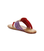 The Bed Stu Yoli is a flat leather thong sandal with a tan sole, red foot strap, purple and tan woven leather sides, and a cushioned insole for all-day comfort.