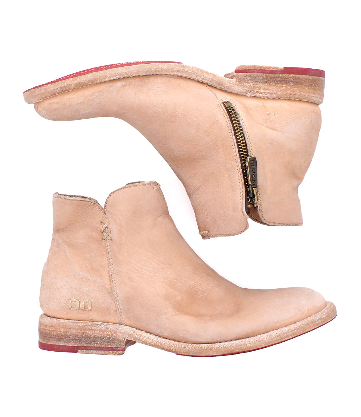 A pair of Bed Stu Yurisa tan leather ankle boots with side zippers, stacked heels, red soles, a rugged Vibram outsole, and visible stitching are shown against a white background.
