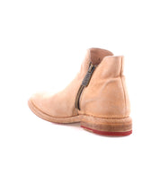 The Bed Stu Yurisa is a tan leather ankle boot featuring a Vibram outsole, side zipper, low heel, and slightly worn finish, shown from the back and side against a white background.