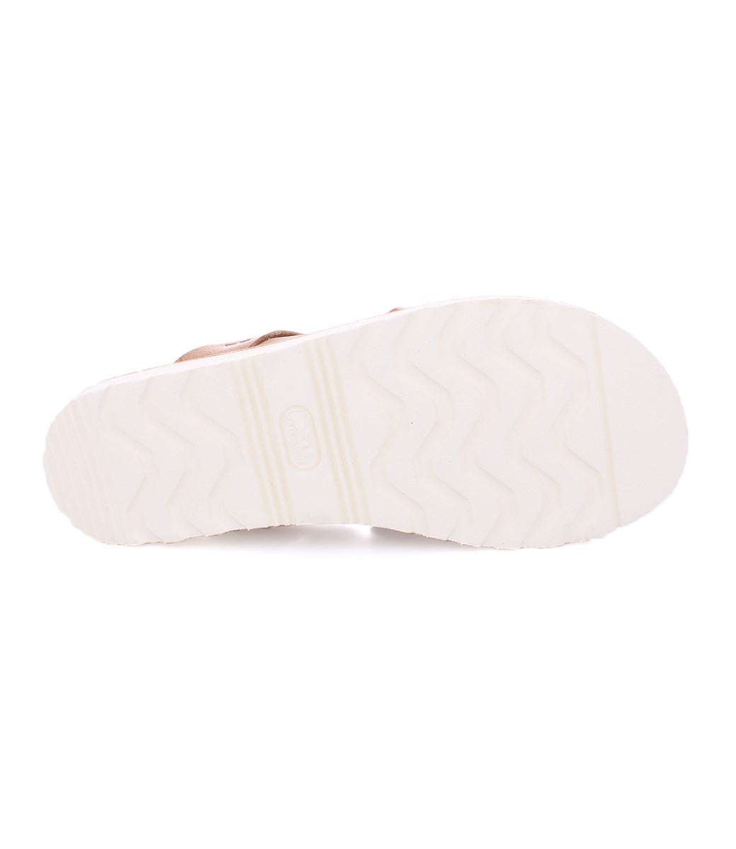 White rubber sole of a Bed Stu slide sandal named Abraham Light, with a wavy tread pattern and brand logo embossed in the center, against a white background.