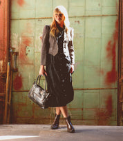 A woman in a leather black dress holding a Bed Stu Ace purse.
