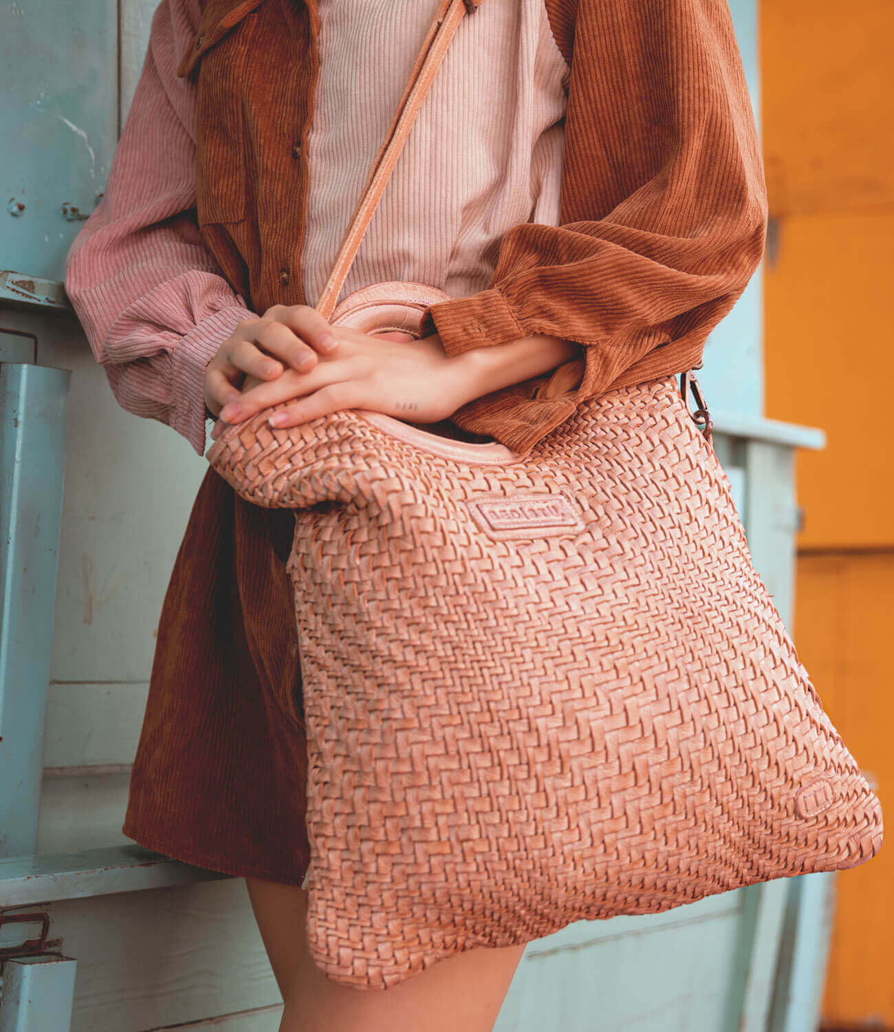 A woman is holding a pink woven Adele bag by Bed Stu.