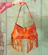 A woman carrying a Bed Stu Advice leather bag adorned with fringes.