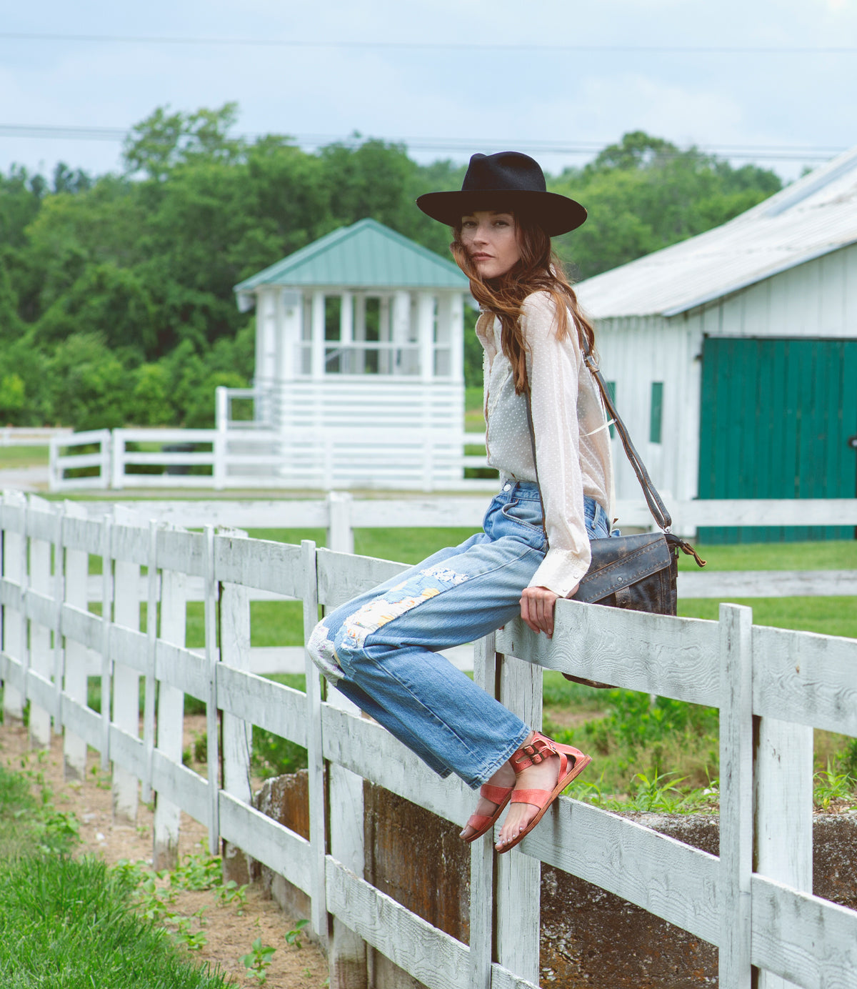 A woman wearing the Bed Stu hat leaning on a fence.