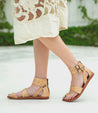 A woman wearing Bed Stu tan sandals and a lace dress.