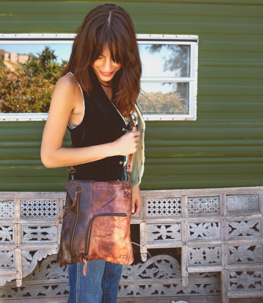 A woman is standing in front of a trailer holding a Bed Stu bag.