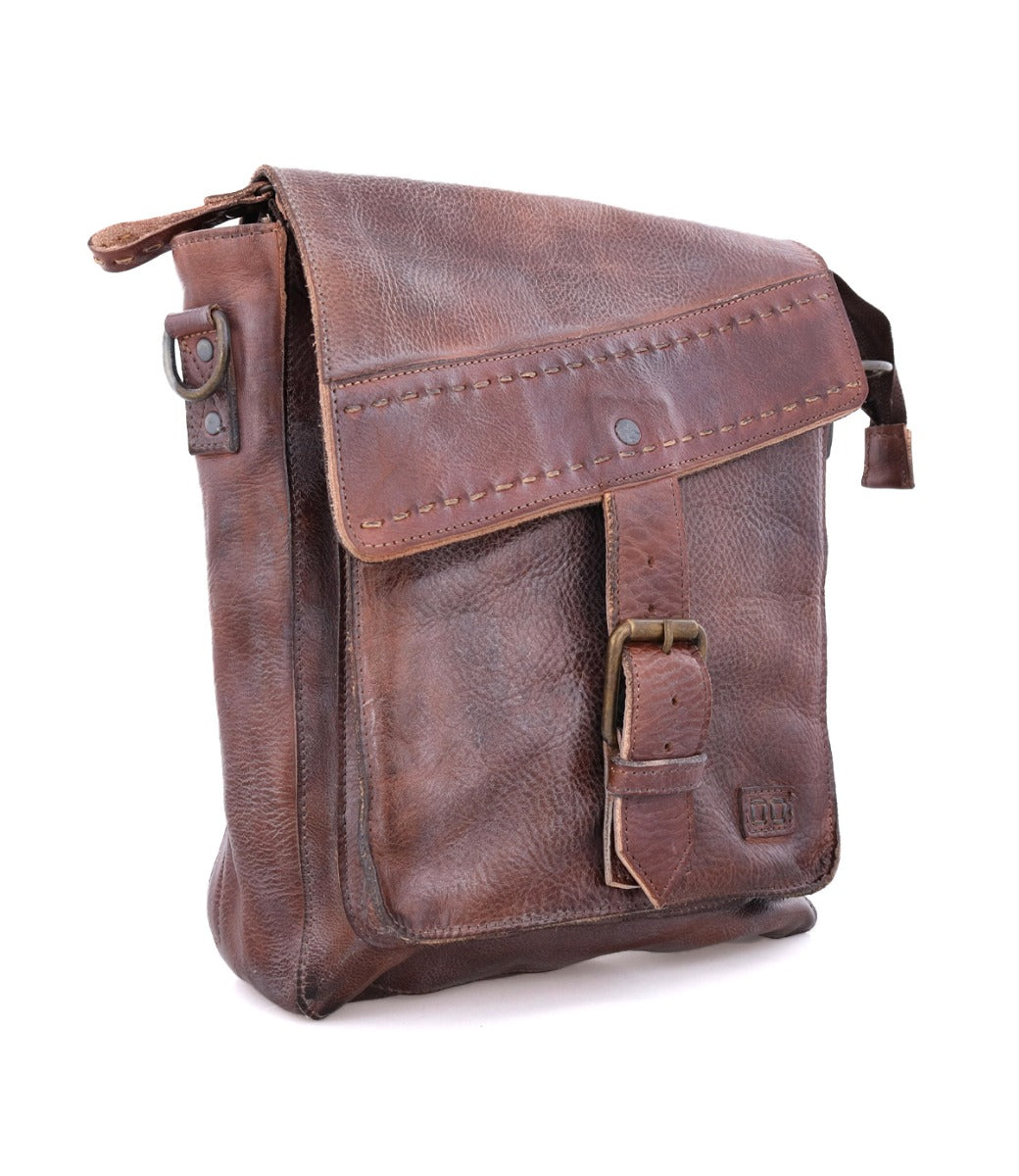 A worn brown leather Ainhoa LTC crossbody handbag by Bed Stu with a buckle closure, standing upright on a white background.