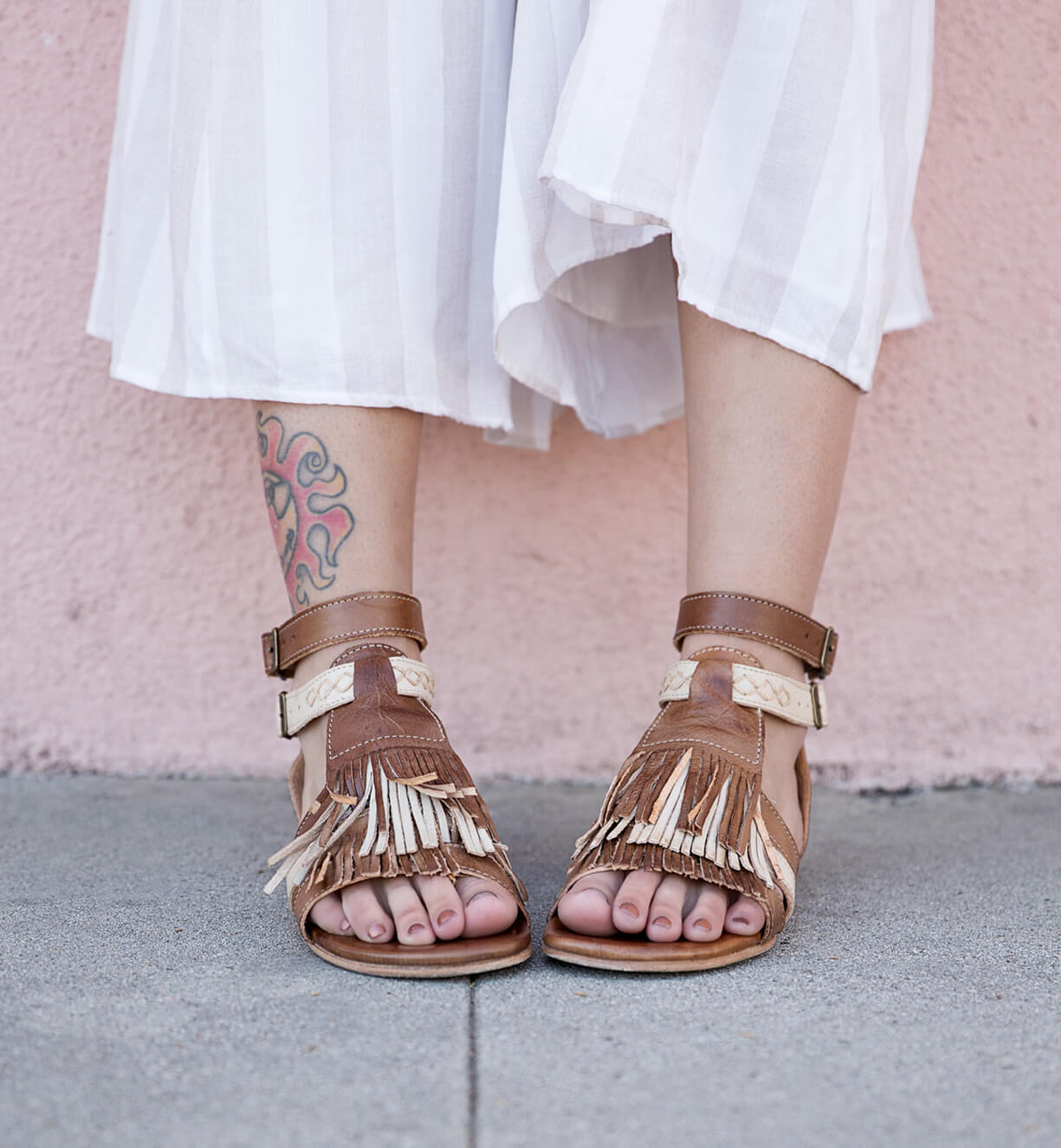 A woman wearing a pair of Bed Stu Alena sandals with fringes.
