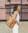 A woman wearing white pants and an Amelie tote bag by Bed Stu.