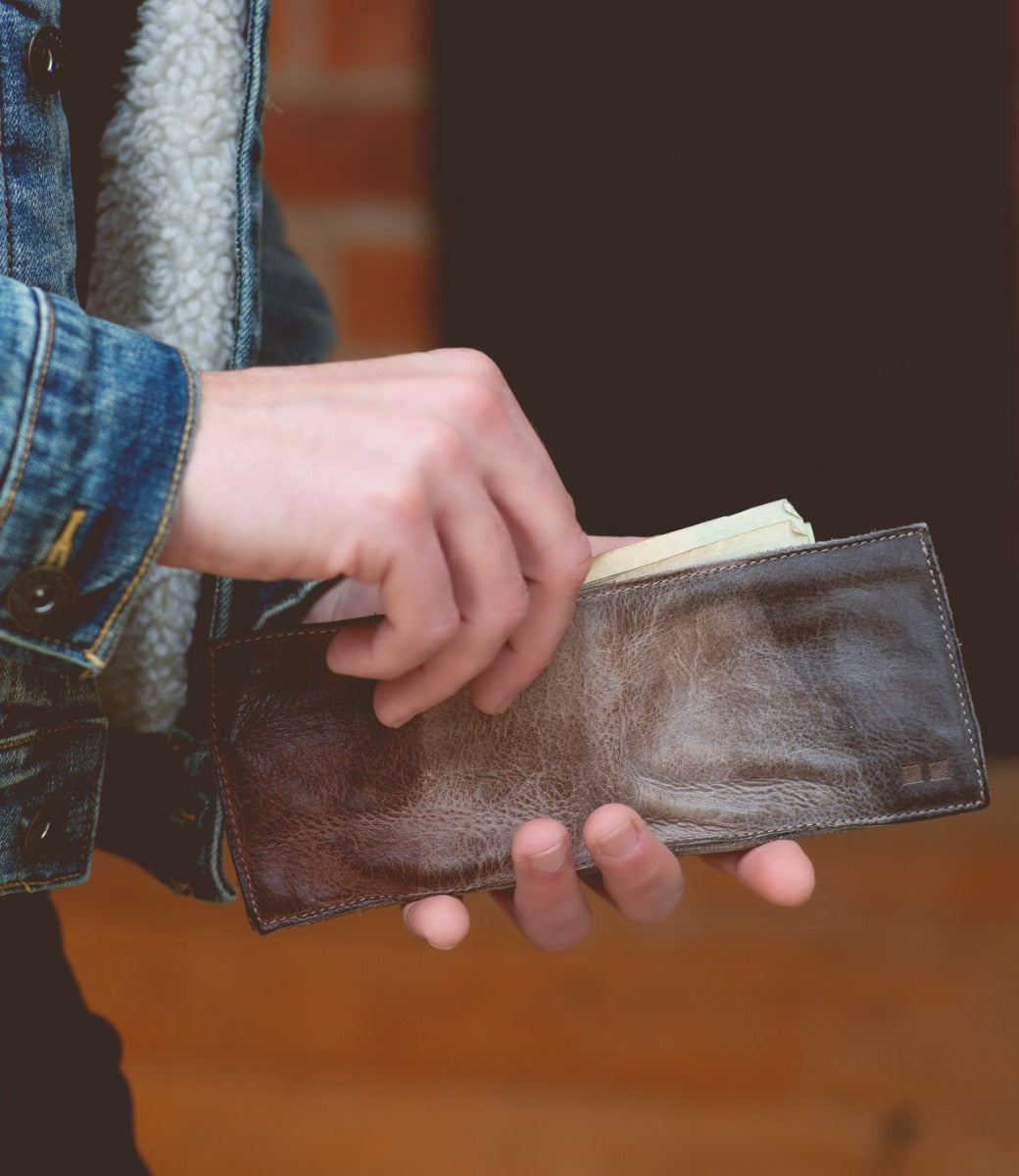 A person holding a Bed Stu brown leather Amidala wallet.