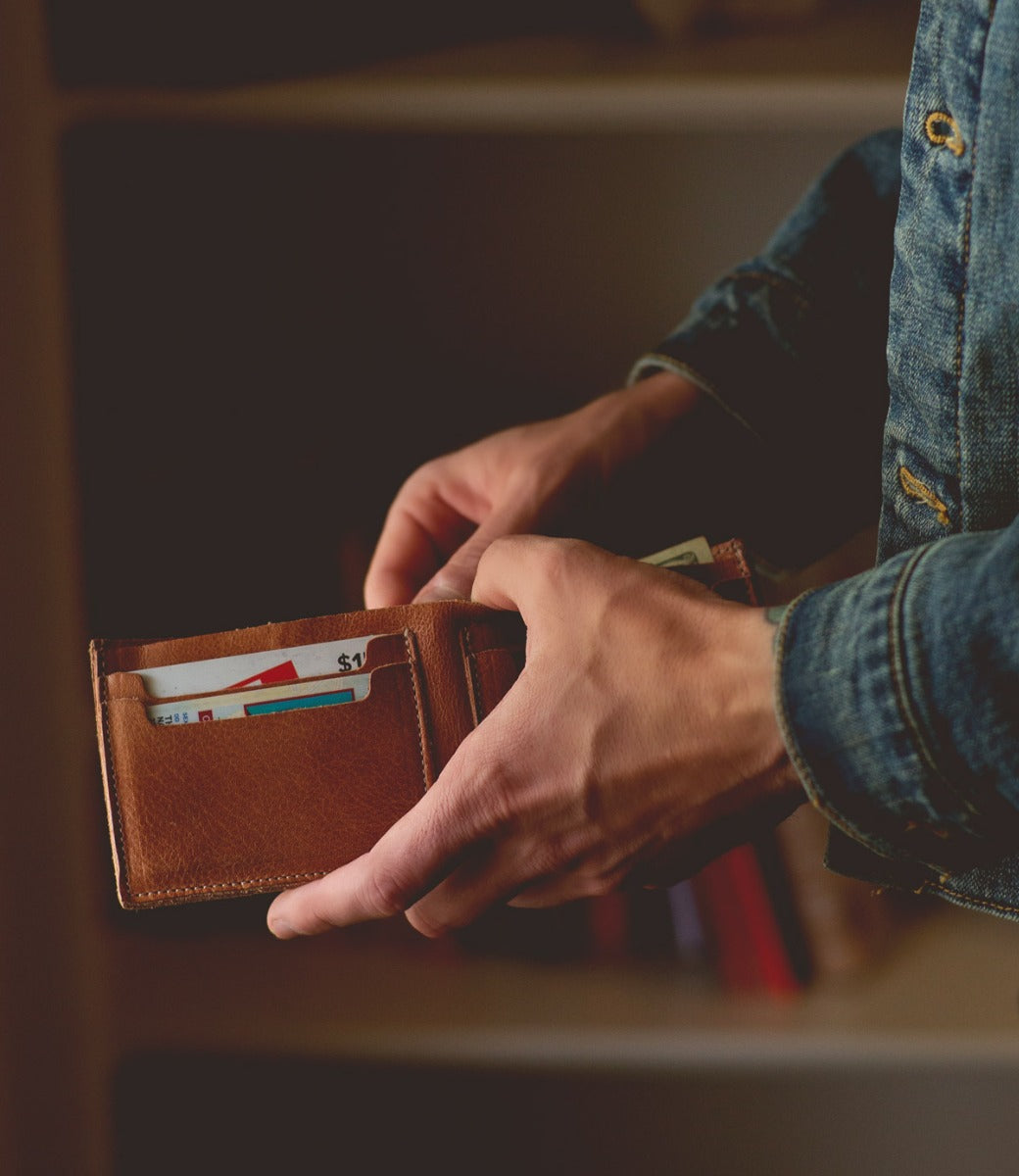 A man holding an Amidala wallet with money in it. (Brand: Bed Stu)